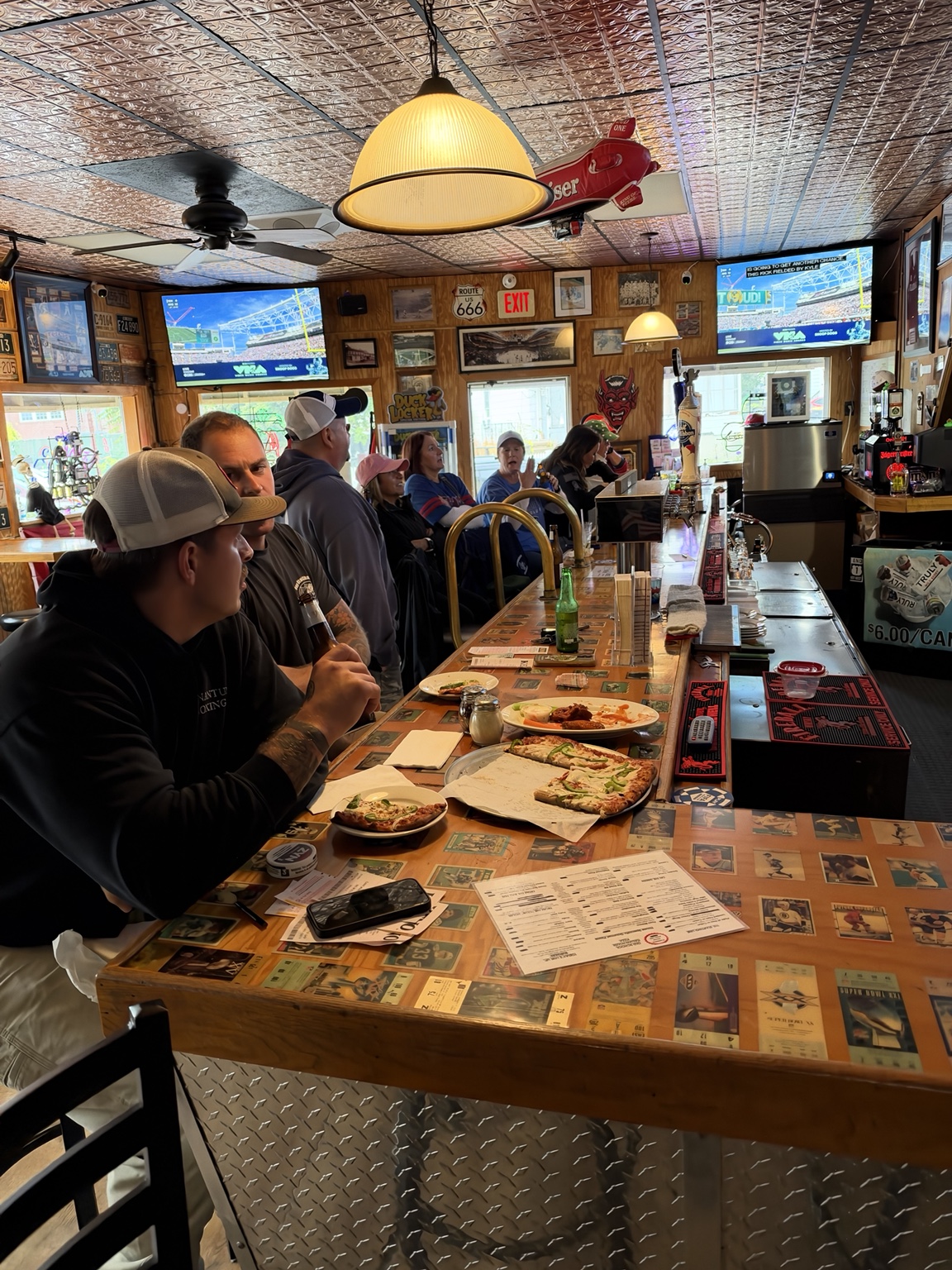 Patrons enjoying pizza and drinks while sports play on the televisions